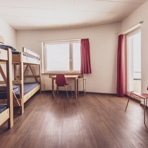 Mehrbettzimmer mit Doppelstockbetten Schreibtisch und Stühlen | © Davos Klosters Mountains 