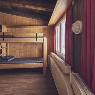 Einfaches Zimmer mit Stockbett, Zusatzbett und Kleiderablage | © Davos Klosters Mountains