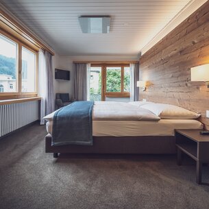 Hotelzimmer mit Doppelbett und grossen Fenstern mit Aussicht | © Davos Klosters Mountains